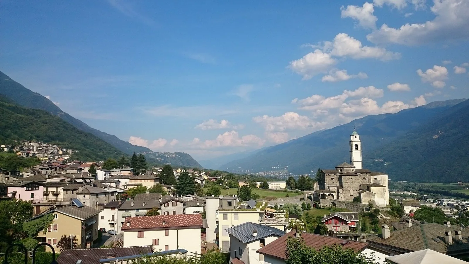 Veduta di Berbenno di Valtellina con il campanile della chiesa di Santa Maria Assunta e le montagne della valle