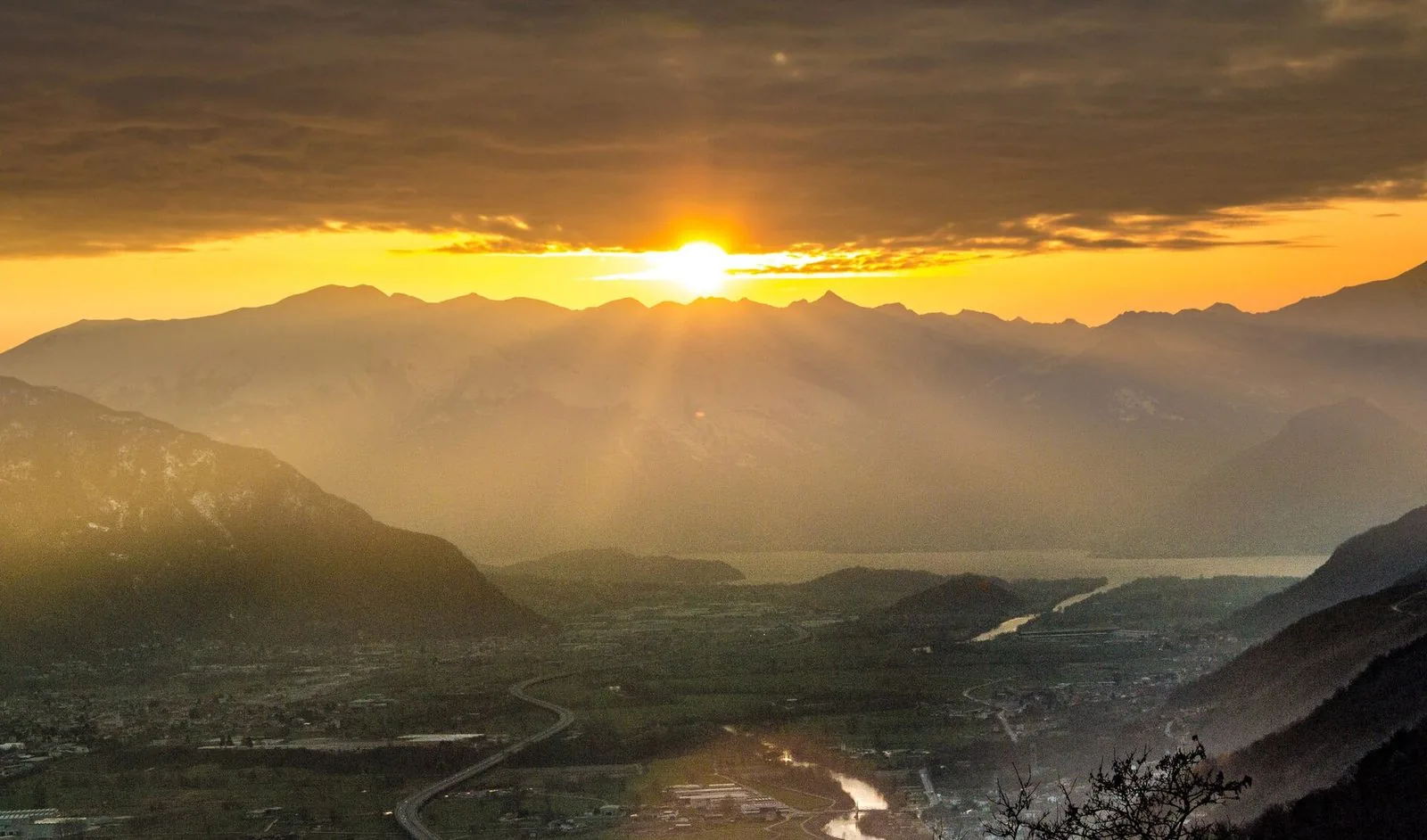 La bassa Valtellina vista dall'alto al tramonto, con la strada a scorrimento veloce e il fiume Adda nel fondovalle